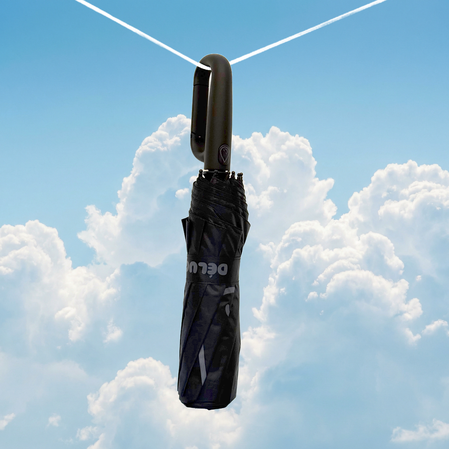 black umbrella hanging from a string against a blue sky with clouds