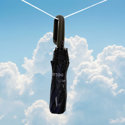 black umbrella hanging from a string against a blue sky with clouds