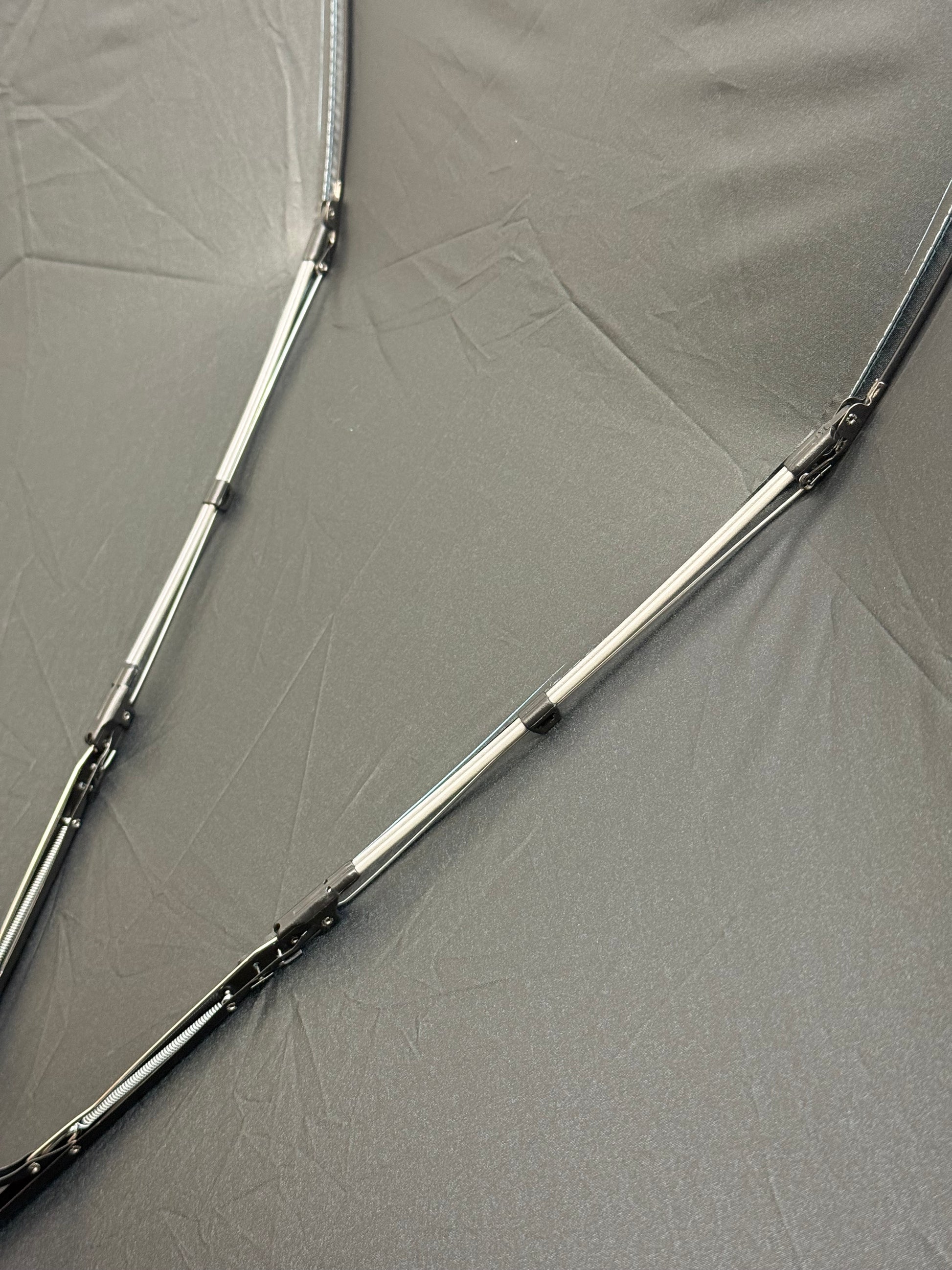 Close-up of an umbrella's ribs with visible stitching and material texture.