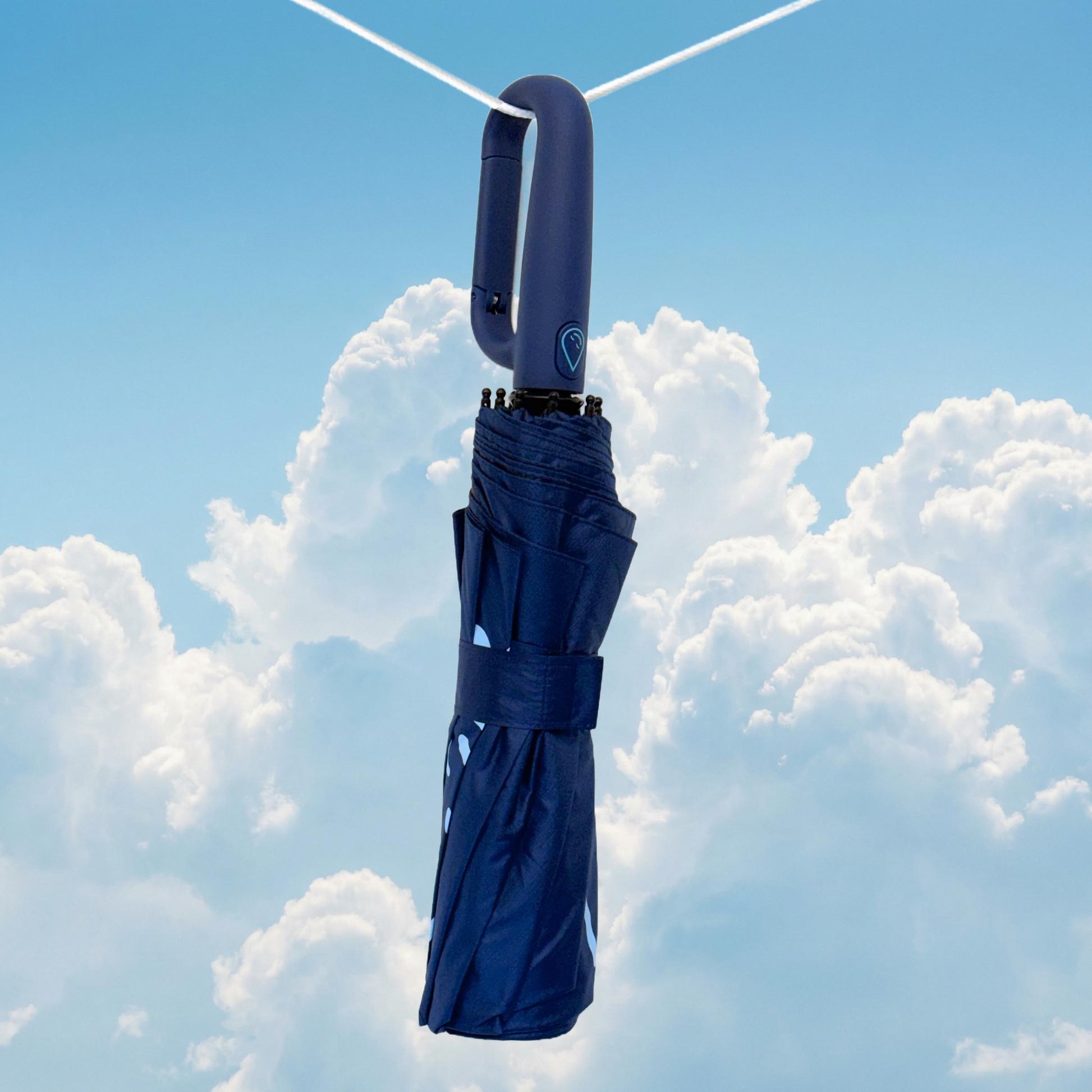 Navy umbrella hanging from a clothesline against a blue sky with clouds