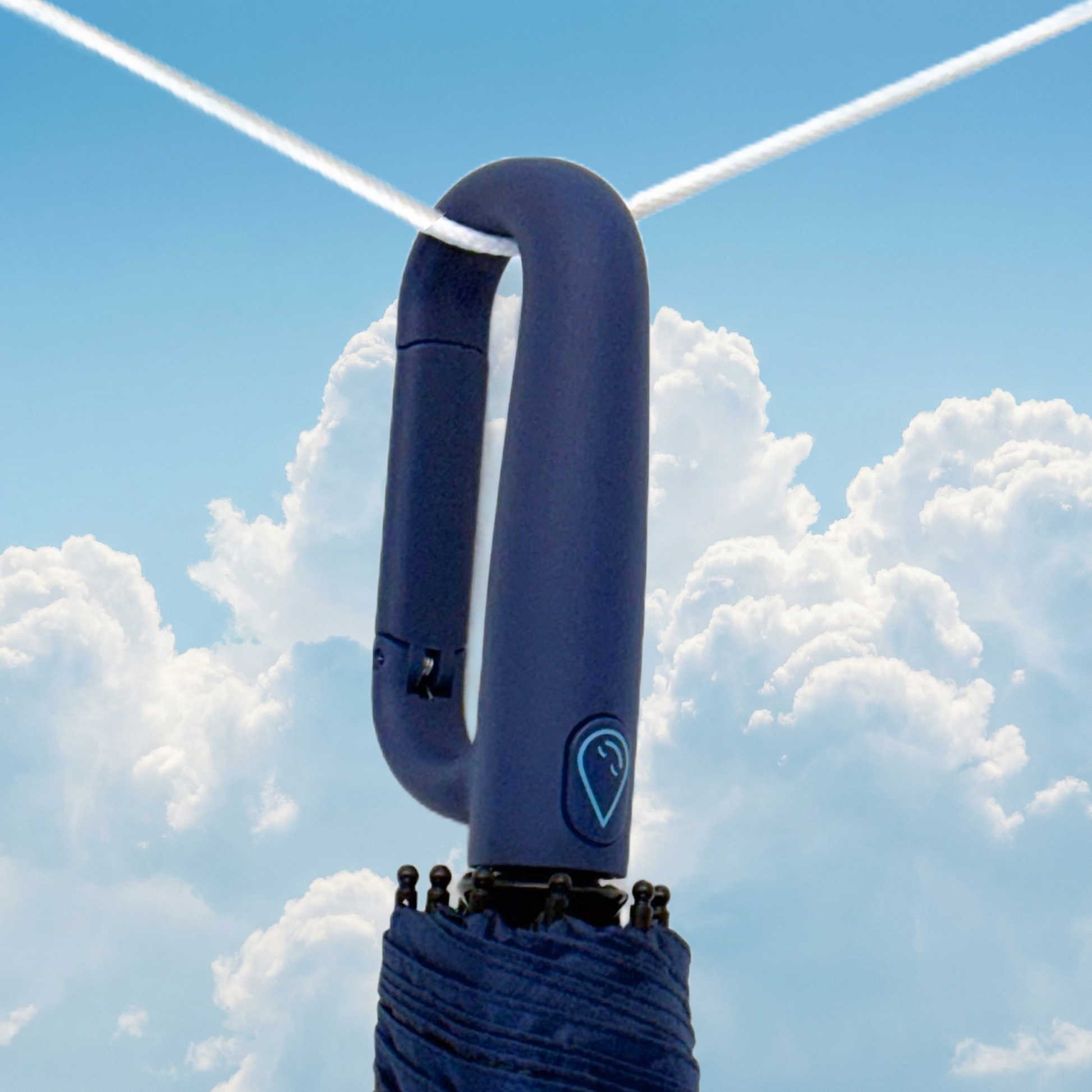 Navy clip umbrella handle against a blue sky with clouds
