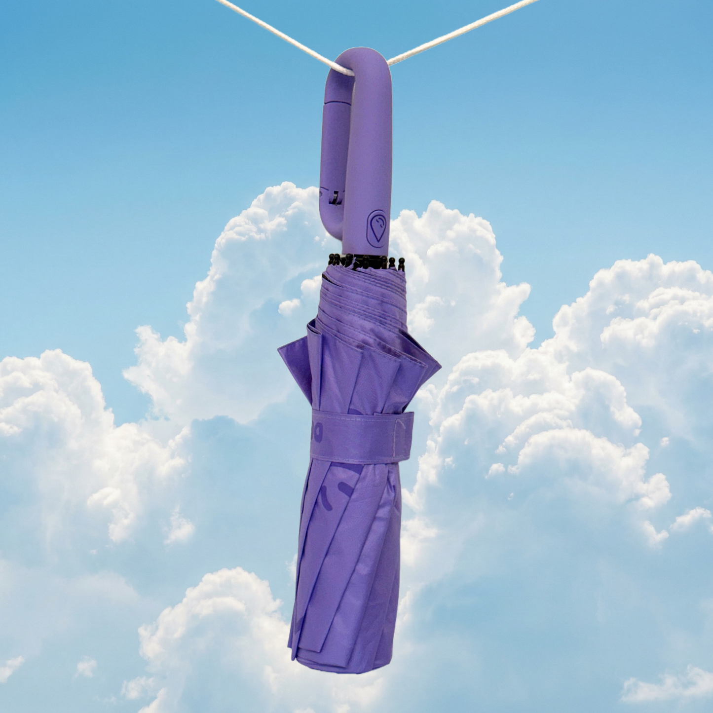 Lilac umbrella hanging from a clothesline against a blue sky with clouds