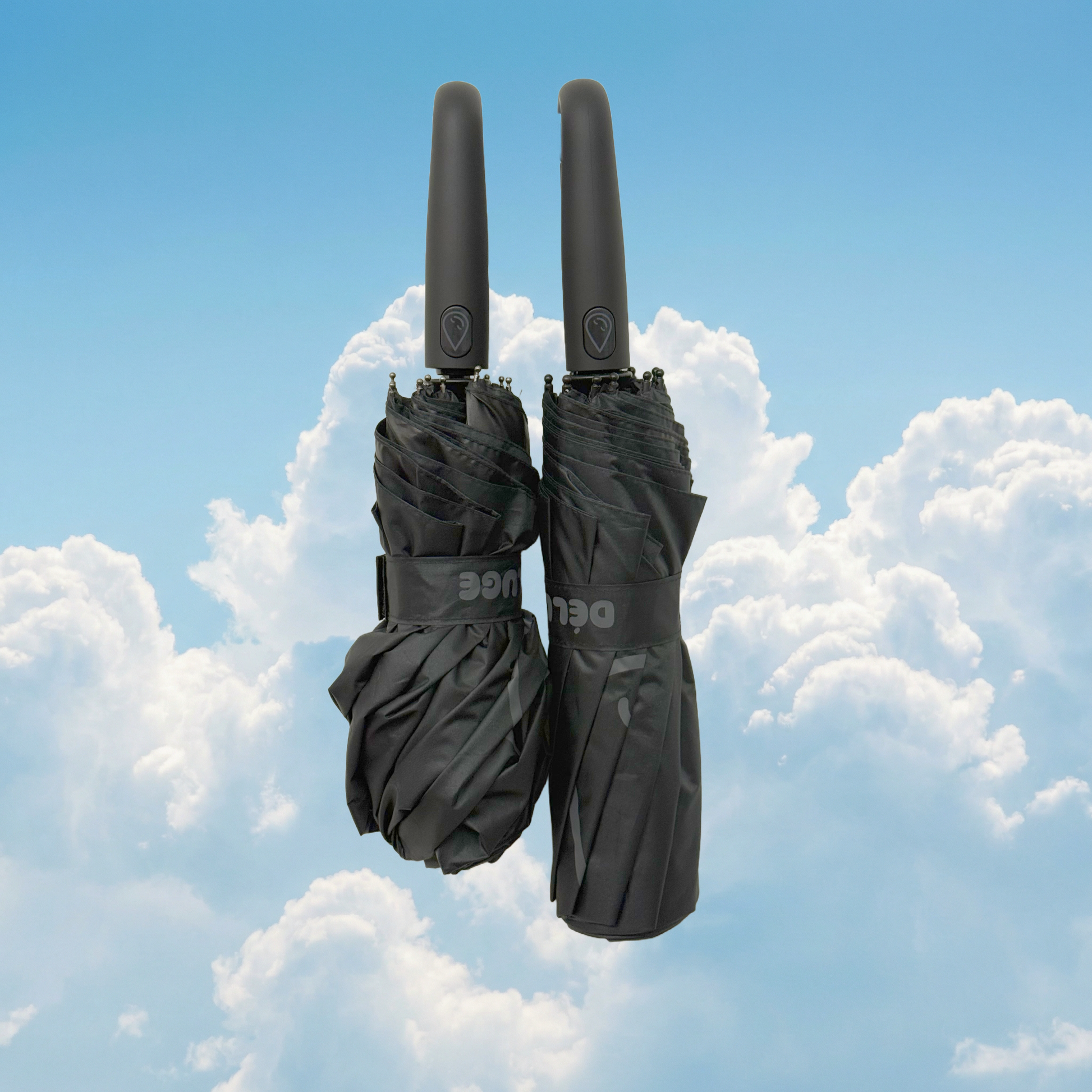 Two black umbrellas against a blue sky with clouds